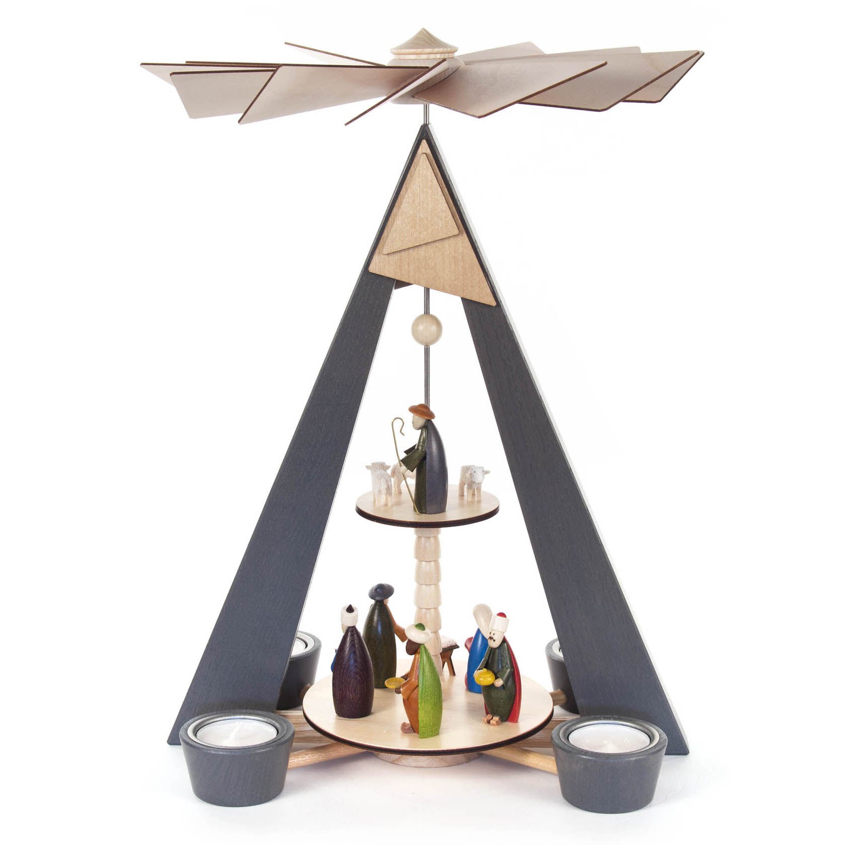 Zweistufige Weihnachtspyramide aus Holz, grau mit farbigen Figuren der Geburt Christi. Enthält Teelichtplätze und einen Flügelrotor oben.