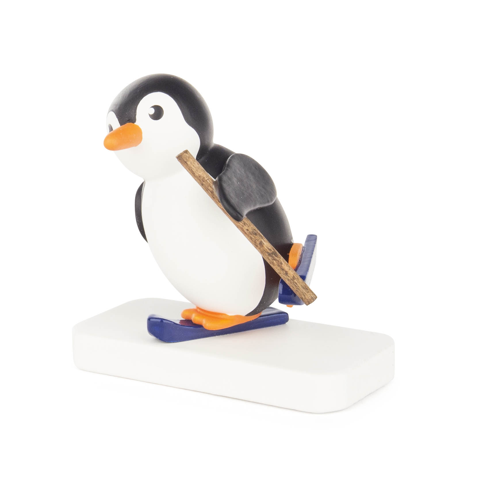 A small toy penguin balancing on blue skis with a wooden stick, depicted on a white base.