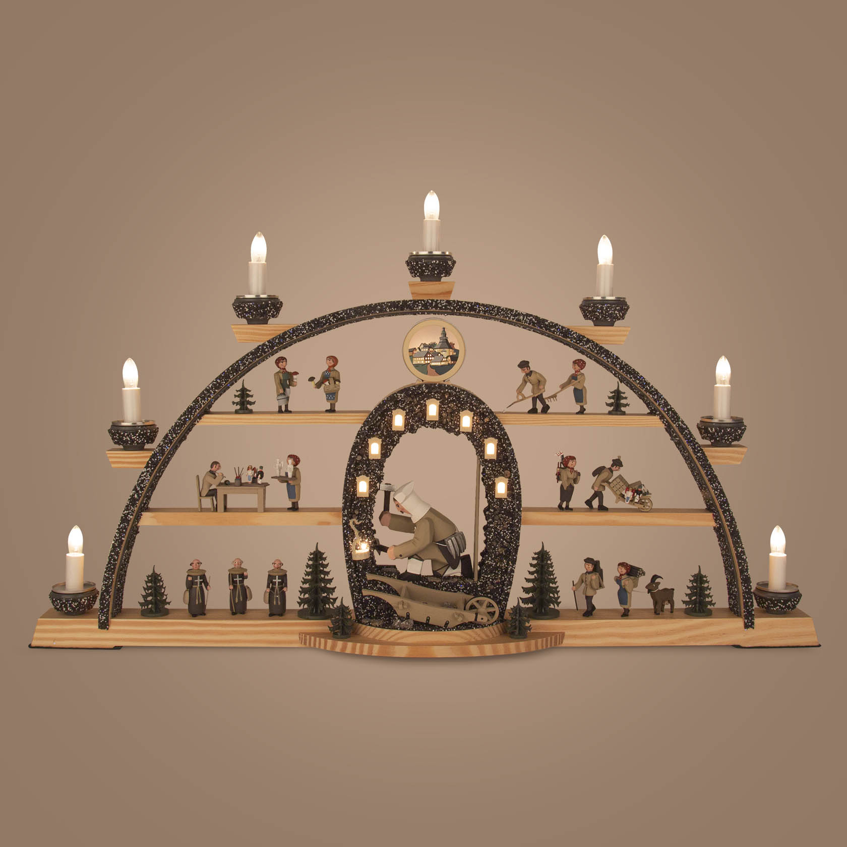 Ein detaillierter Schwibbogen mit einem Bergmann, der eine Grubenlampe hält, umgeben von mehreren Bergleuten in verschiedenen Arbeitsszenen und beleuchtet von sieben Kerzen.