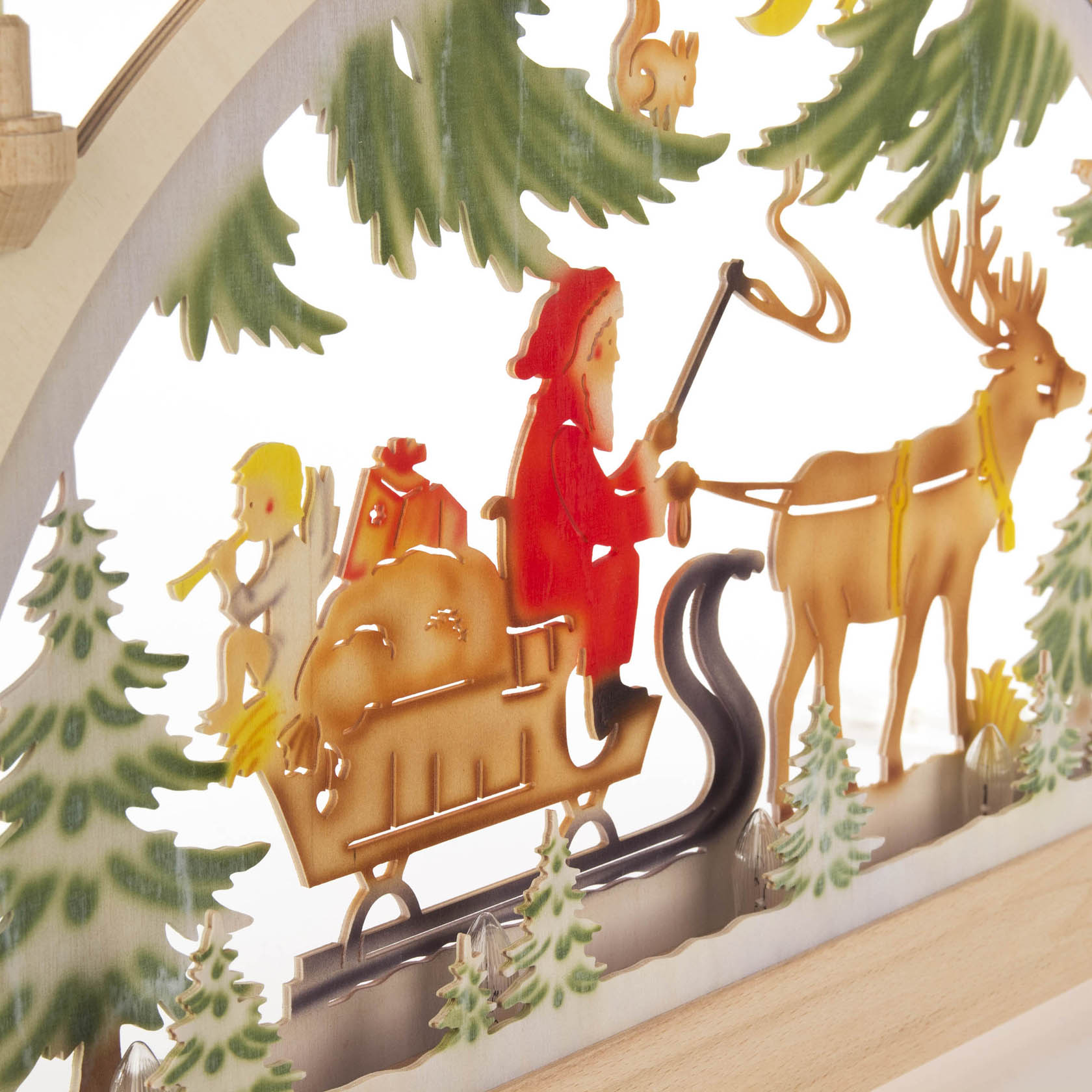 A colorful electric Schwibbogen depicting St. Nicholas on a sled, pulled by a reindeer, with toys in the background and illuminated by lights.