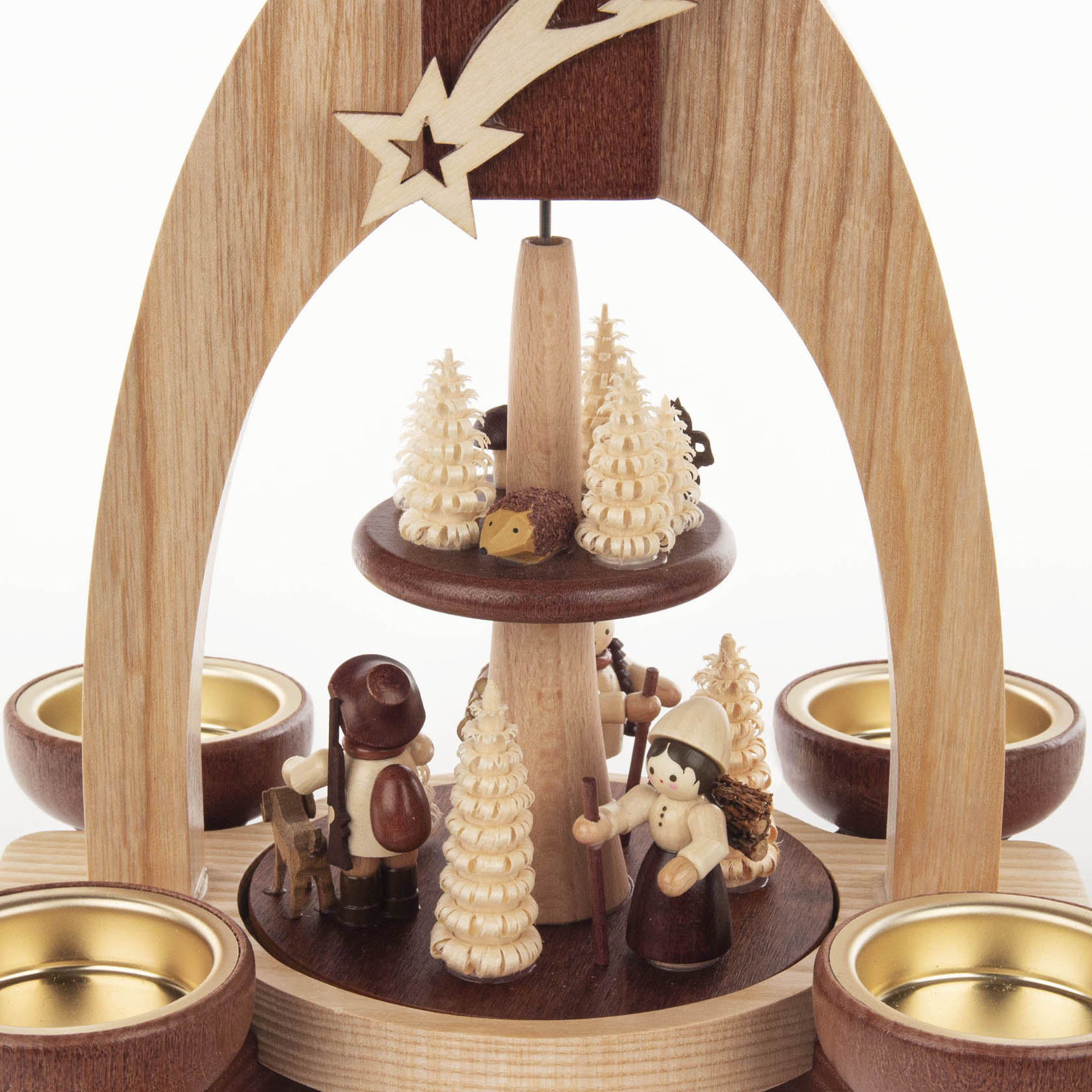 Two-tier wooden pyramid with natural finish featuring carved forest figures including a hiker, a woman, and small forest animals, surrounded by candle holders.