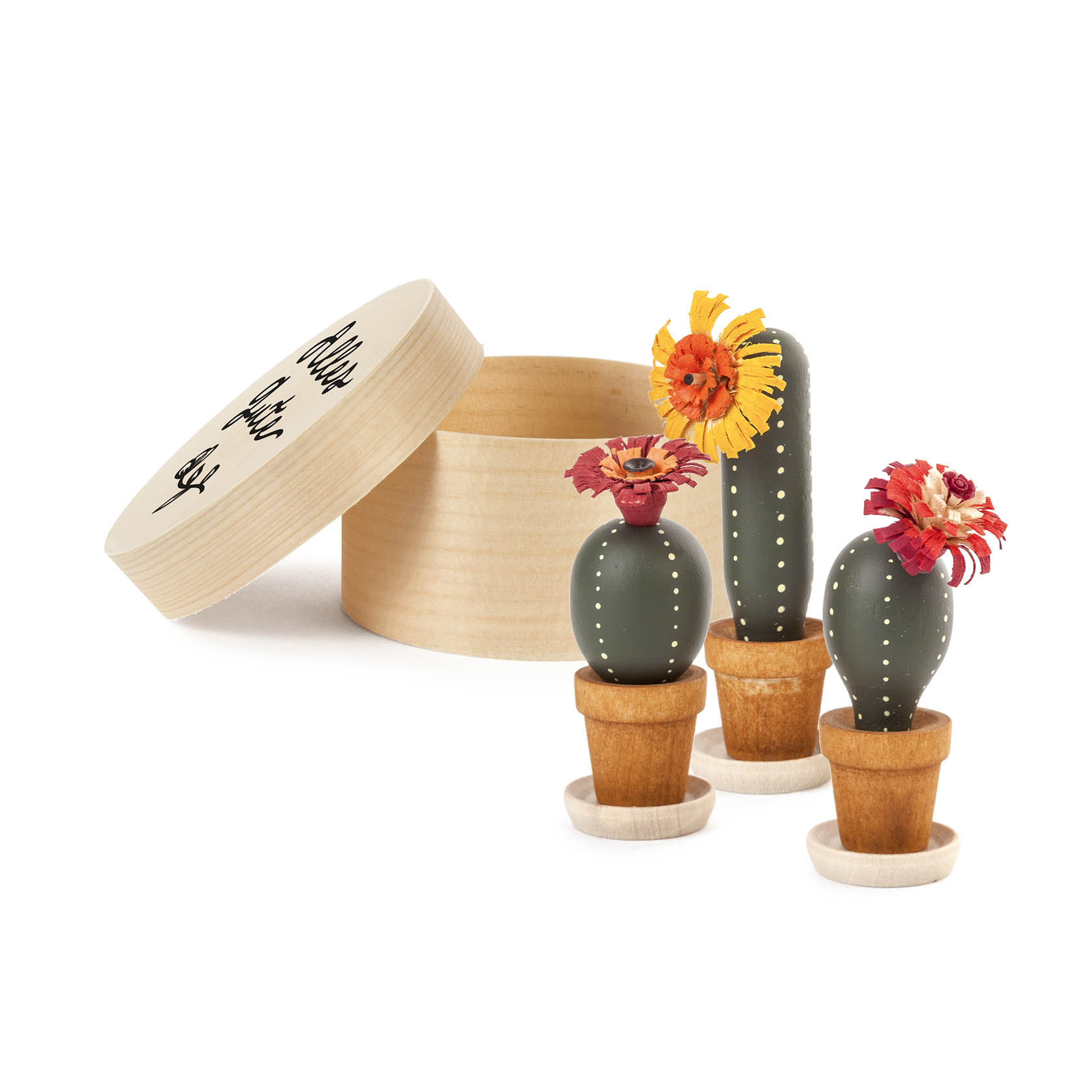 Three miniature cacti made of wood inside a round wooden box with a lid featuring the text 'Alles Gute'. Each cactus has a brightly colored flower.