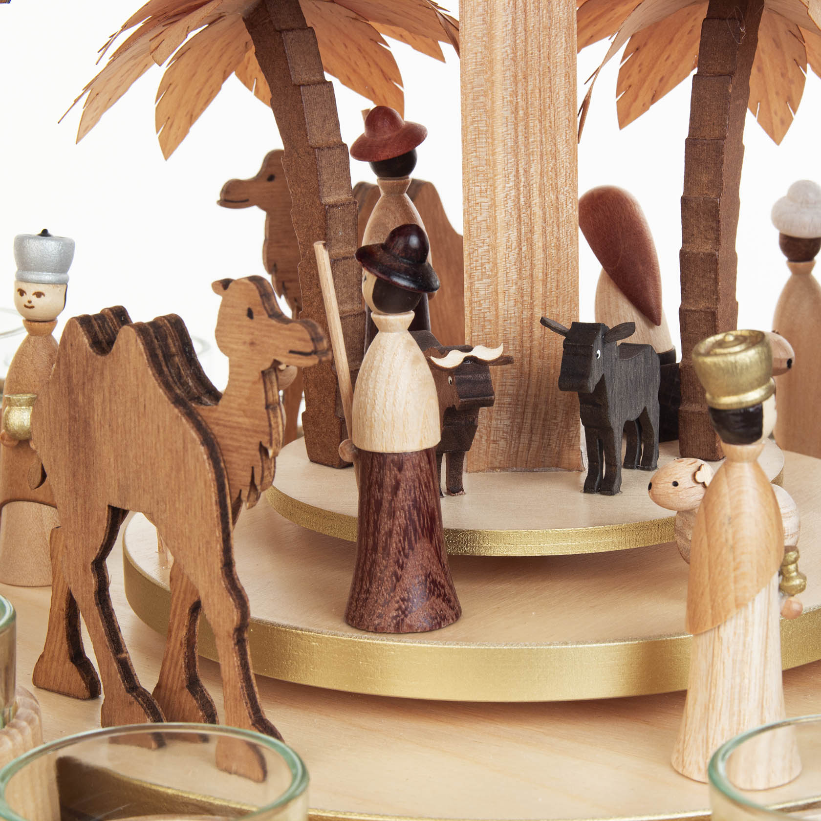 Wooden nativity scene with figures of Mary, Joseph, baby Jesus, shepherds, animals, and two tiered trays for tealights, decorated with palm trees.