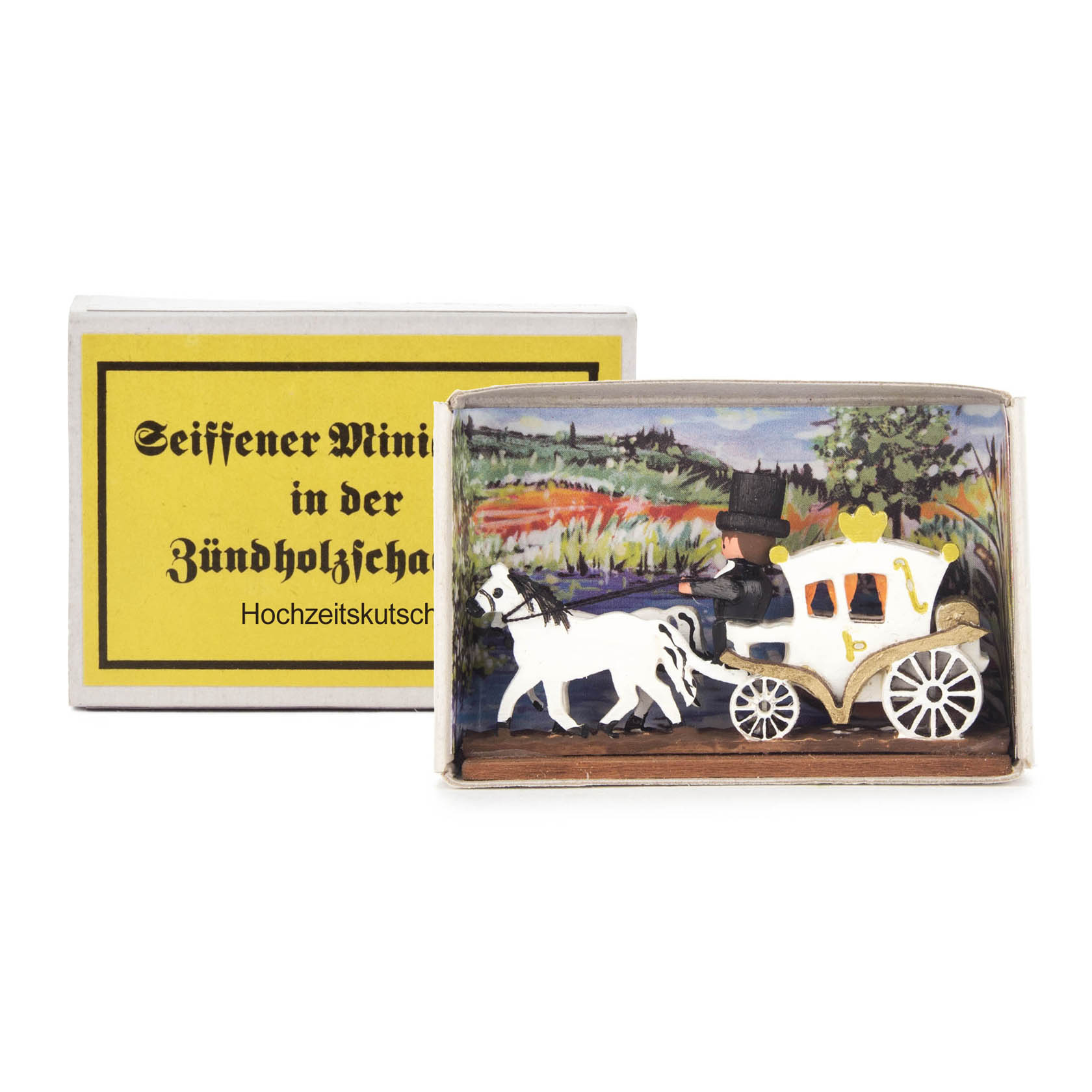 Kleine Holzfigur einer Hochzeitkutsche mit weißem Pferd und einem Kutscher in einem Zylinder, platziert in einer Zündholzschachtel mit gelbem Etikett. im Dregeno Online Shop günstig kaufen