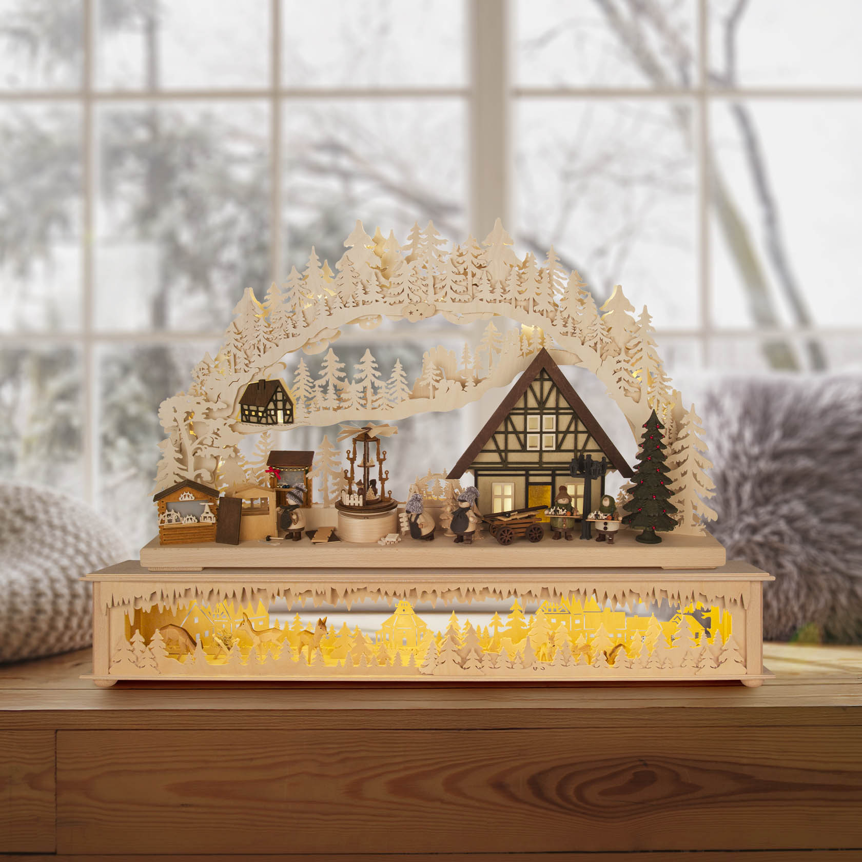 Schwibbogen mit weihnachtlicher Szenerie: Fachwerkhaus, Figuren, Holzbäume und Marktstände. Unten leuchtet eine gelbe Beleuchtung.