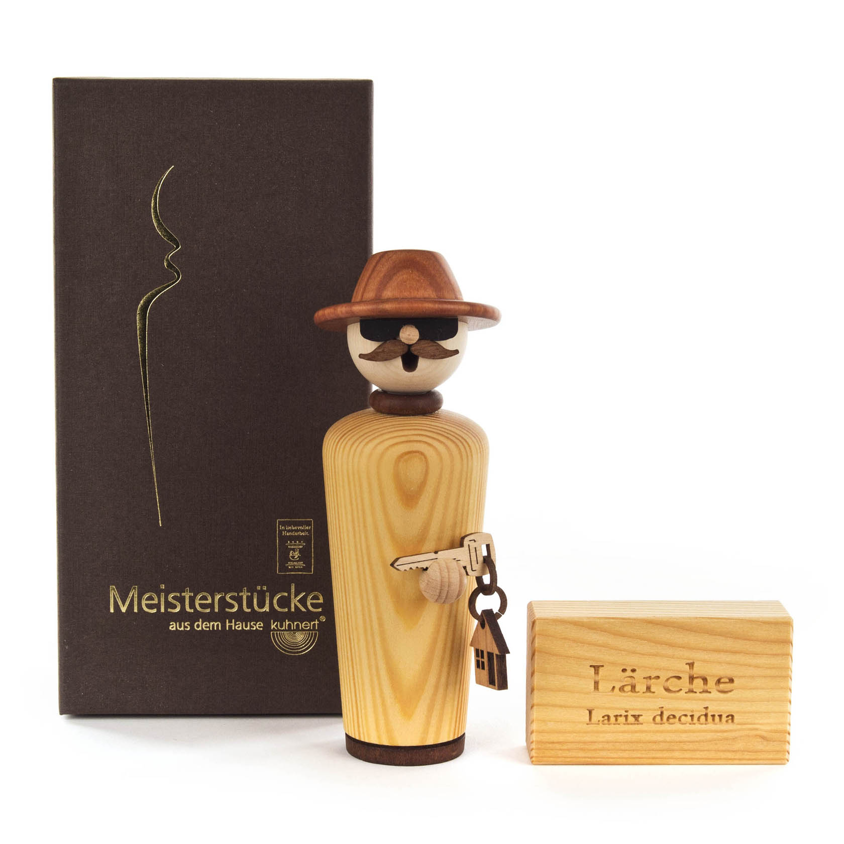 Räucherfigur 'Baumeister' aus Lärchenholz mit Bart, Hut und Schlüsselbund in der Hand. Die Figur steht neben einer Verpackung mit goldener Aufschrift 'Meisterstücke'.