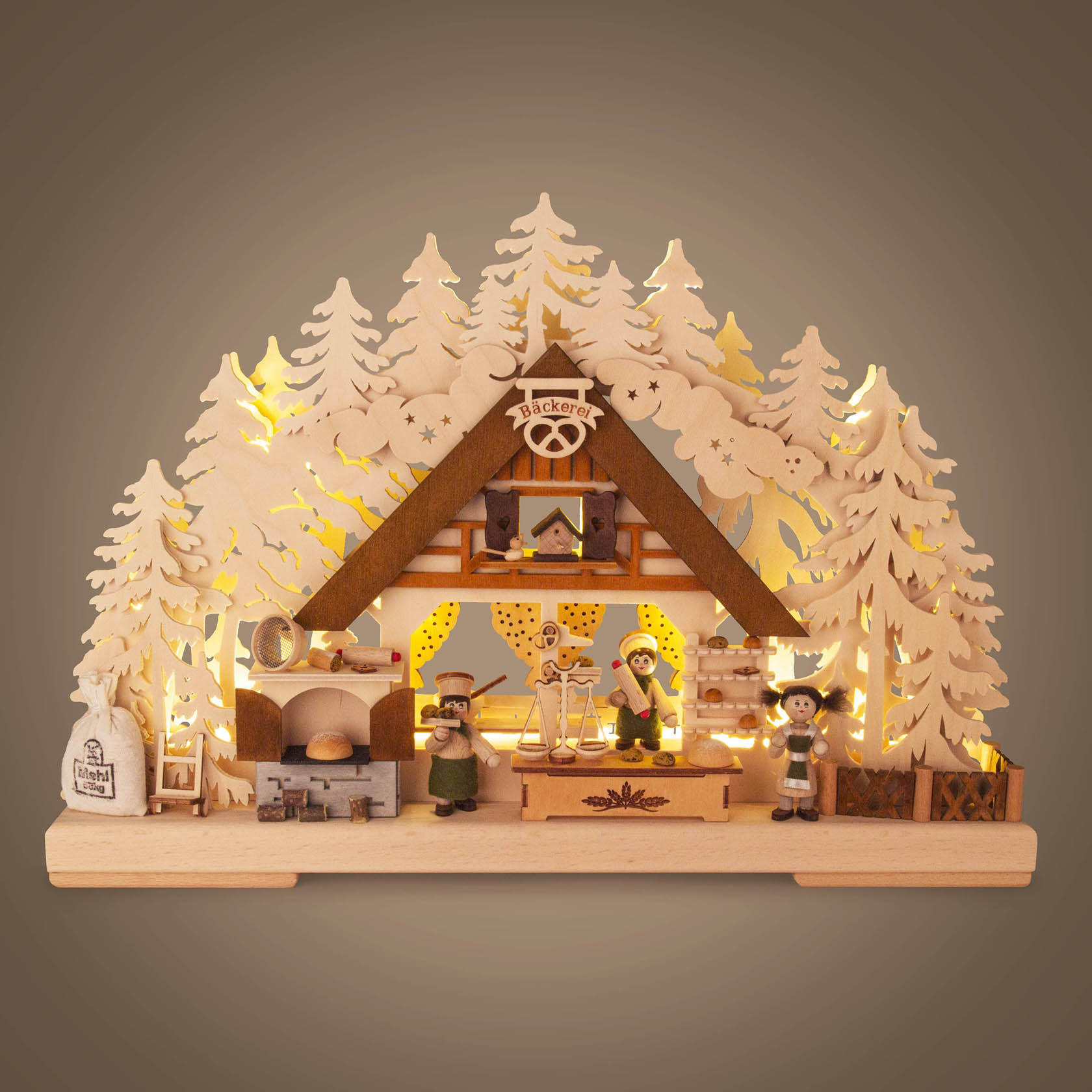 Ein kleiner Schwibbogen, der eine Weihnachtsbäckerei darstellt, elektrisch beleuchtet. Szenen mit Bäcker, Kindern, Ofen und Weihnachtsbaum sind sichtbar.