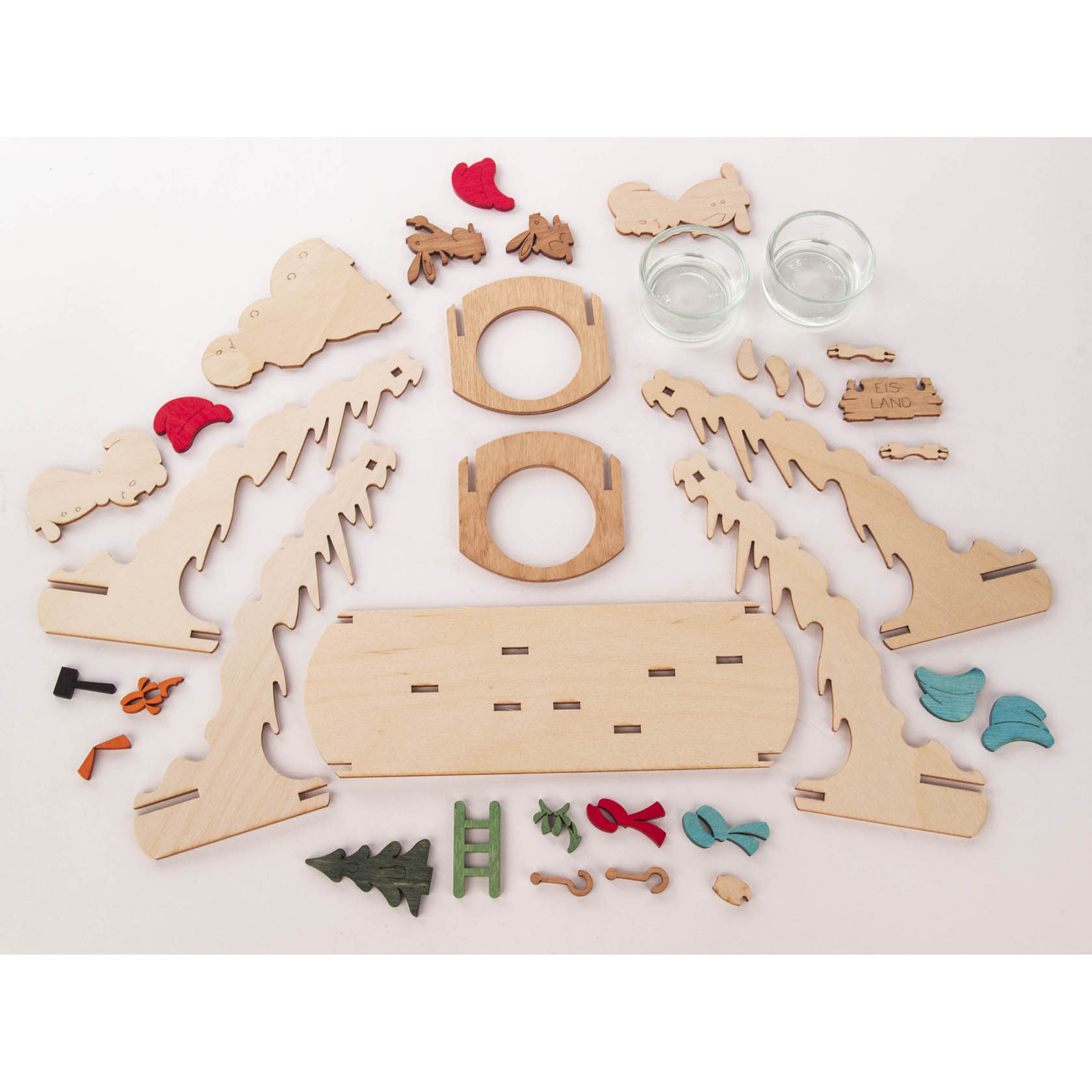 Holz-Bastelset mit verschiedenen Einzelteilen zum Zusammenbau eines Teelichtbogens im Schneemann-Motiv. Teile umfassen Bäume, Schneemannformen und zwei Glasbehälter.