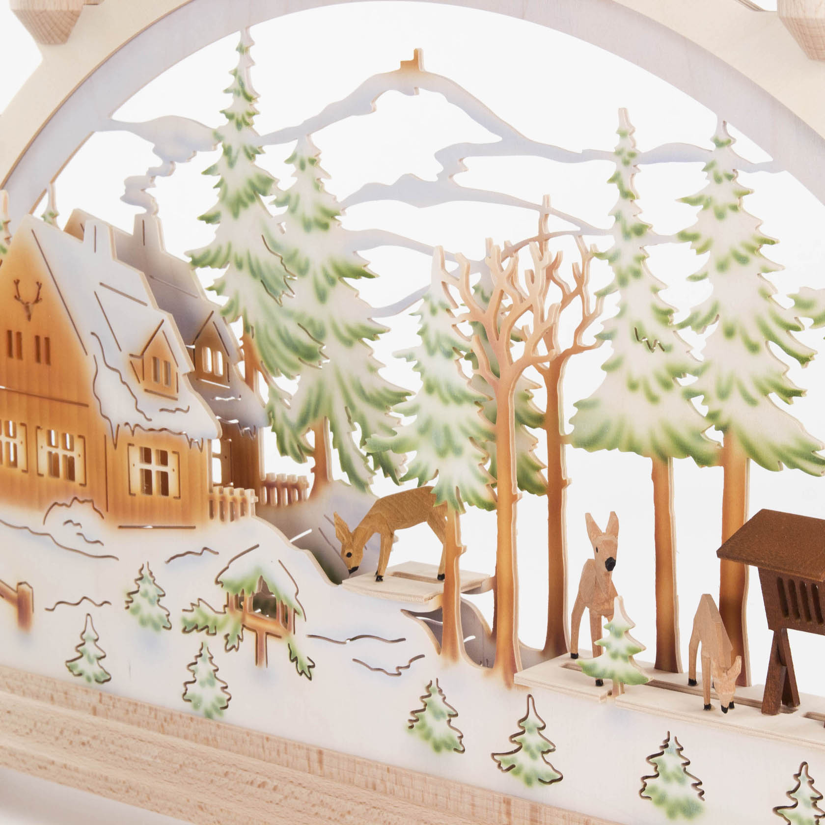 Ein beleuchteter Schwibbogen zeigt ein Forsthaus im Wald, umgeben von Bäumen und Rehen. Die Szenerie ist winterlich und detailreich gestaltet.