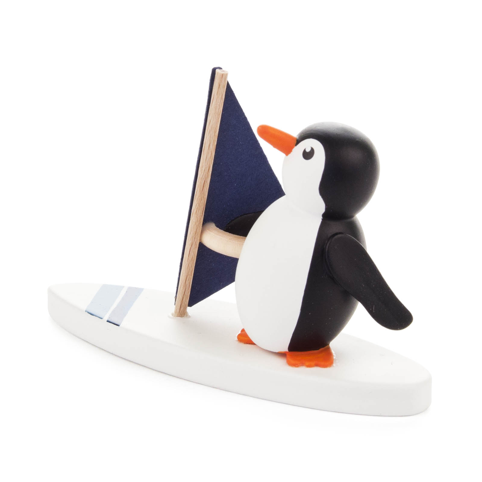Kleine Pinguinfigur aus Holz, die auf einem weißen Surfbrett mit blauem Segel steht. Der Pinguin ist schwarz-weiß mit orangem Schnabel und Füßen.