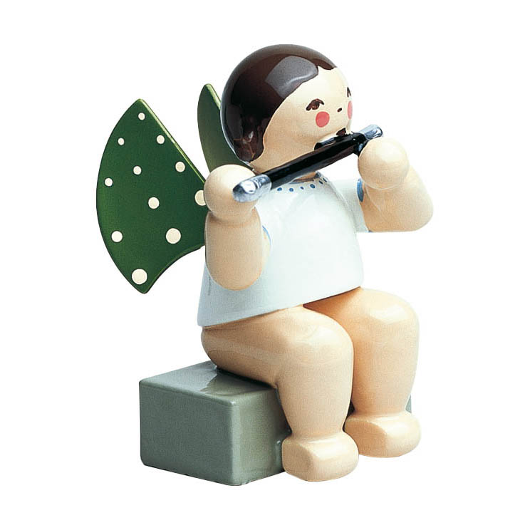 A wooden angel figure with brown hair, painted red cheeks, and green wings with white dots. The angel is sitting on a grey block and playing a black flute. im Dregeno Online Shop günstig kaufen
