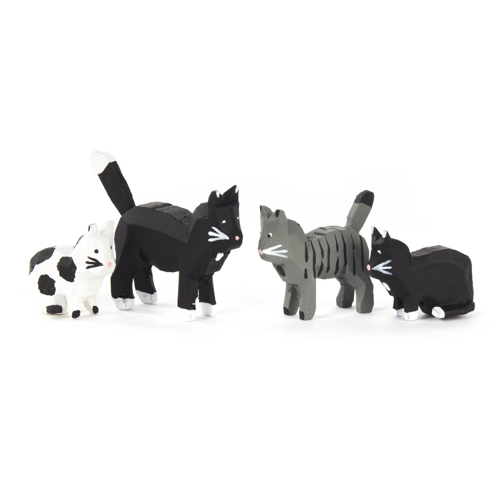 Vier kleine Holzkatzen in schwarz-weiß und grau-schwarz, jede mit individuellen Mustern und Gesichtsausdrücken, stehen nebeneinander. im Dregeno Online Shop günstig kaufen