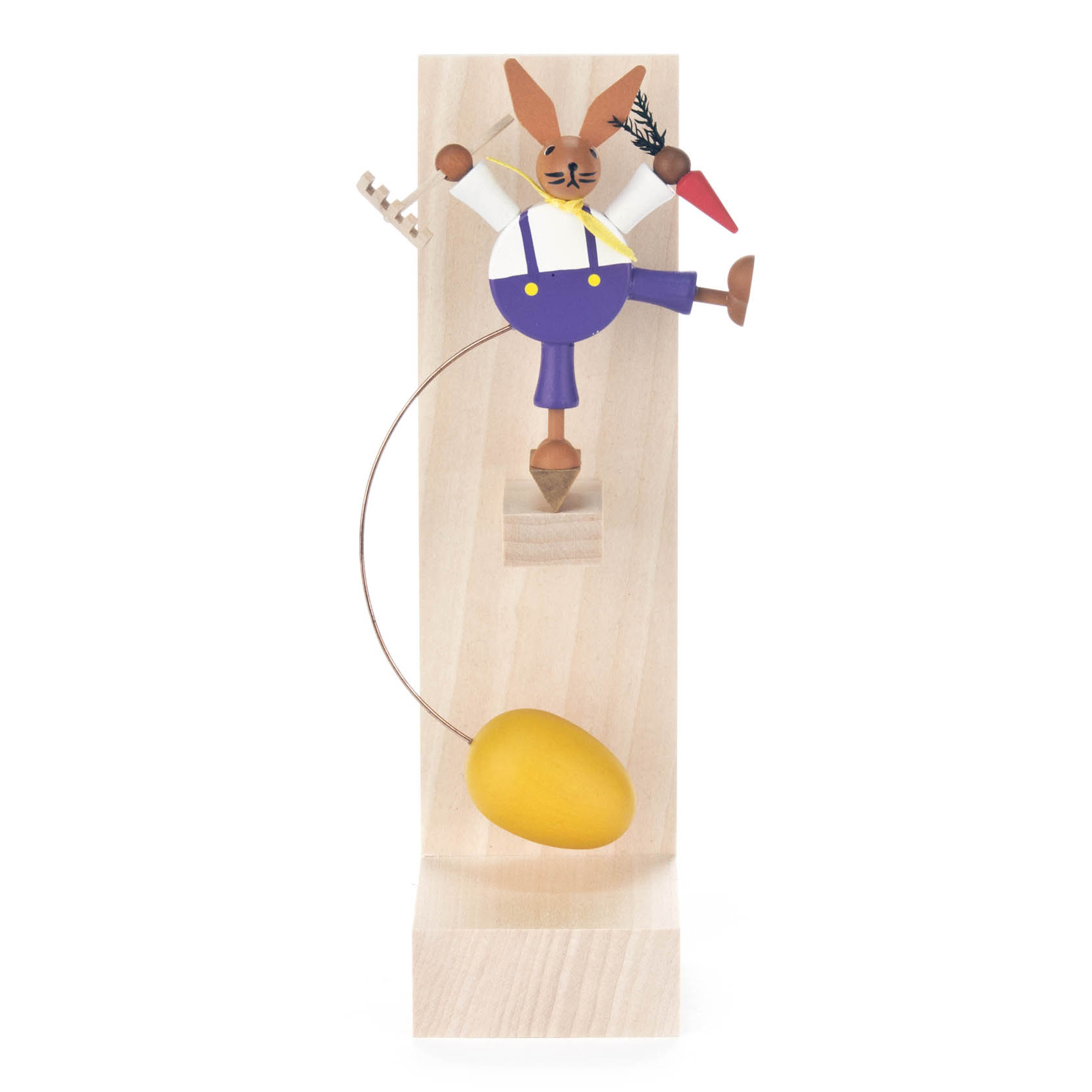Holzfigur eines Osterhasen als Gärtner in Latzhose, der auf einem Holzbrett balanciert. Der Hase hält eine Möhre und eine kleine Harke. Unter ihm schwingt ein gelbes Ei. im Dregeno Online Shop günstig kaufen