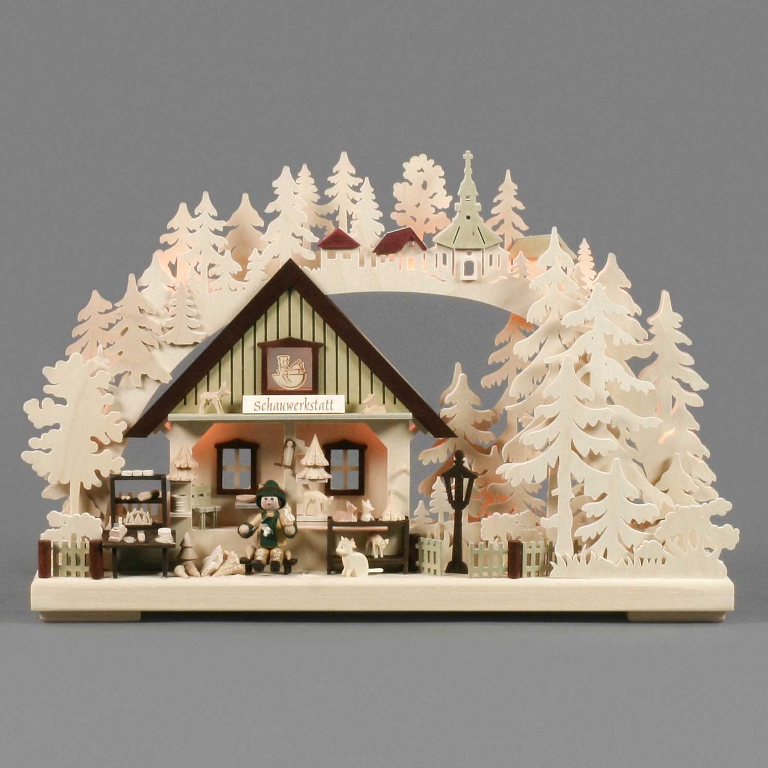 Wooden arch candle holder depicting a craftsman's workshop scene with a woodcarver, surrounded by trees and small animals, softly lit.