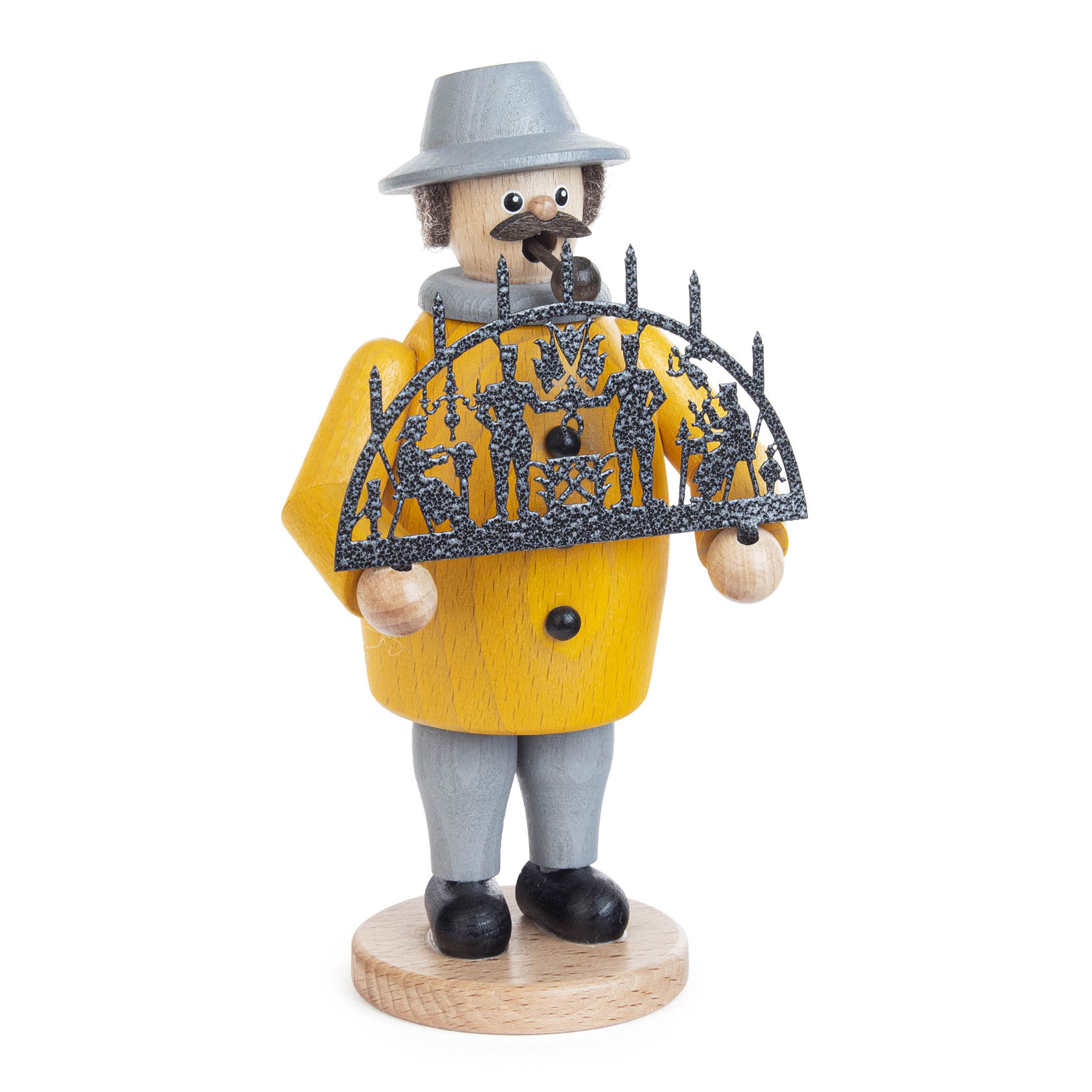 Ein traditioneller Räuchermann in gelbem Mantel und grauem Hut mit Holzpfeife hält einen dekorativen schwarzen Schwibbogen in den Händen.