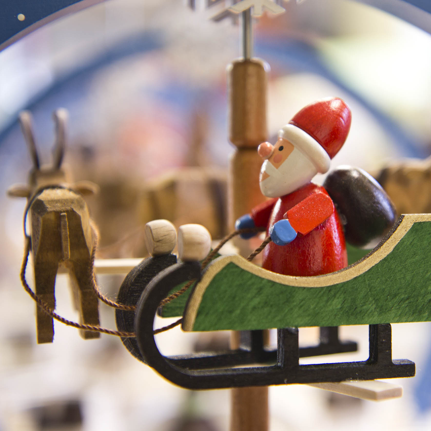 Close-up of a colorful wooden Christmas pyramid featuring a Santa figurine in a green sleigh with reindeer.