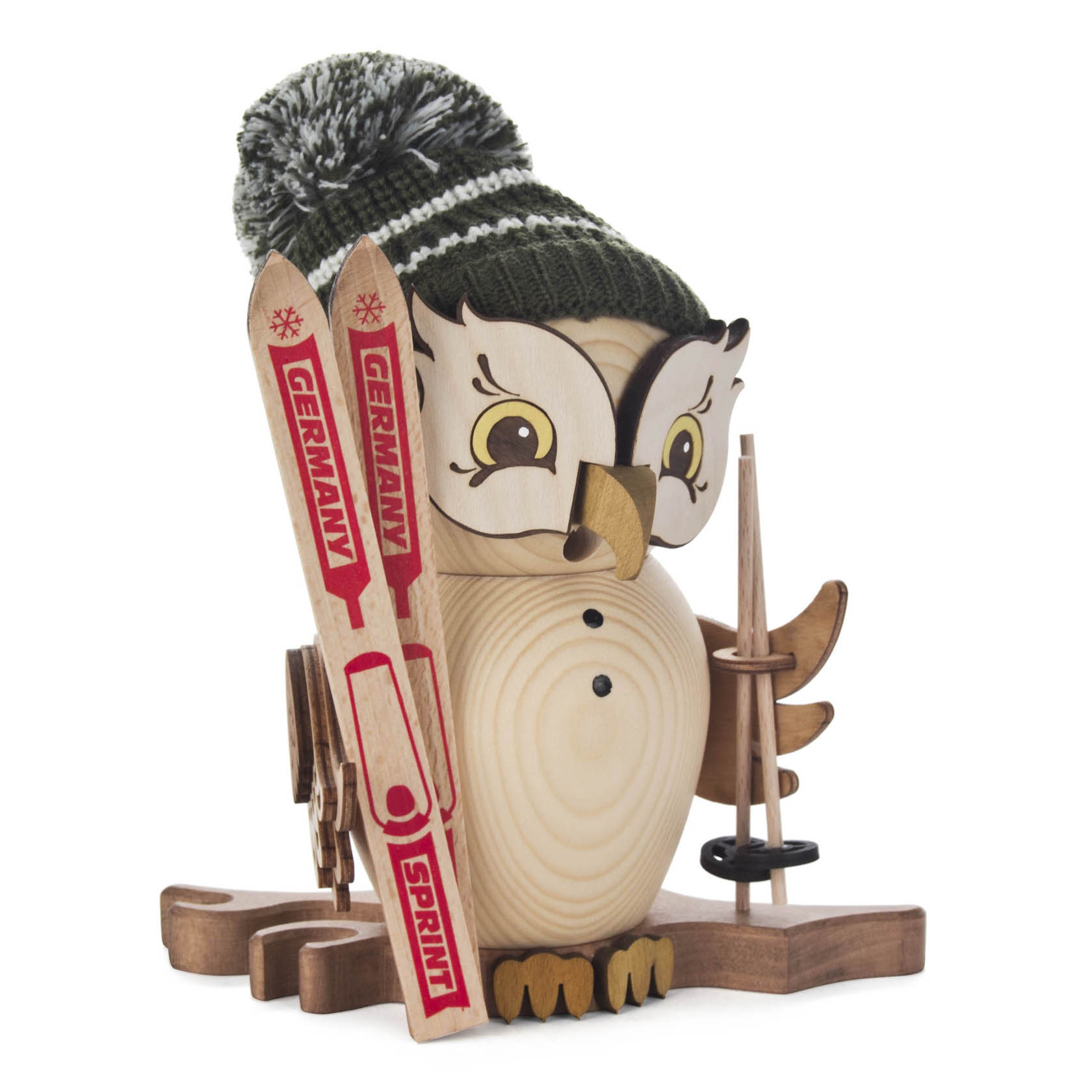 Holzeule mit Skifahrermontur, trägt eine grüne Strickmütze, hält Skistöcke, hat Skier mit der Aufschrift 'Germany' neben sich.
