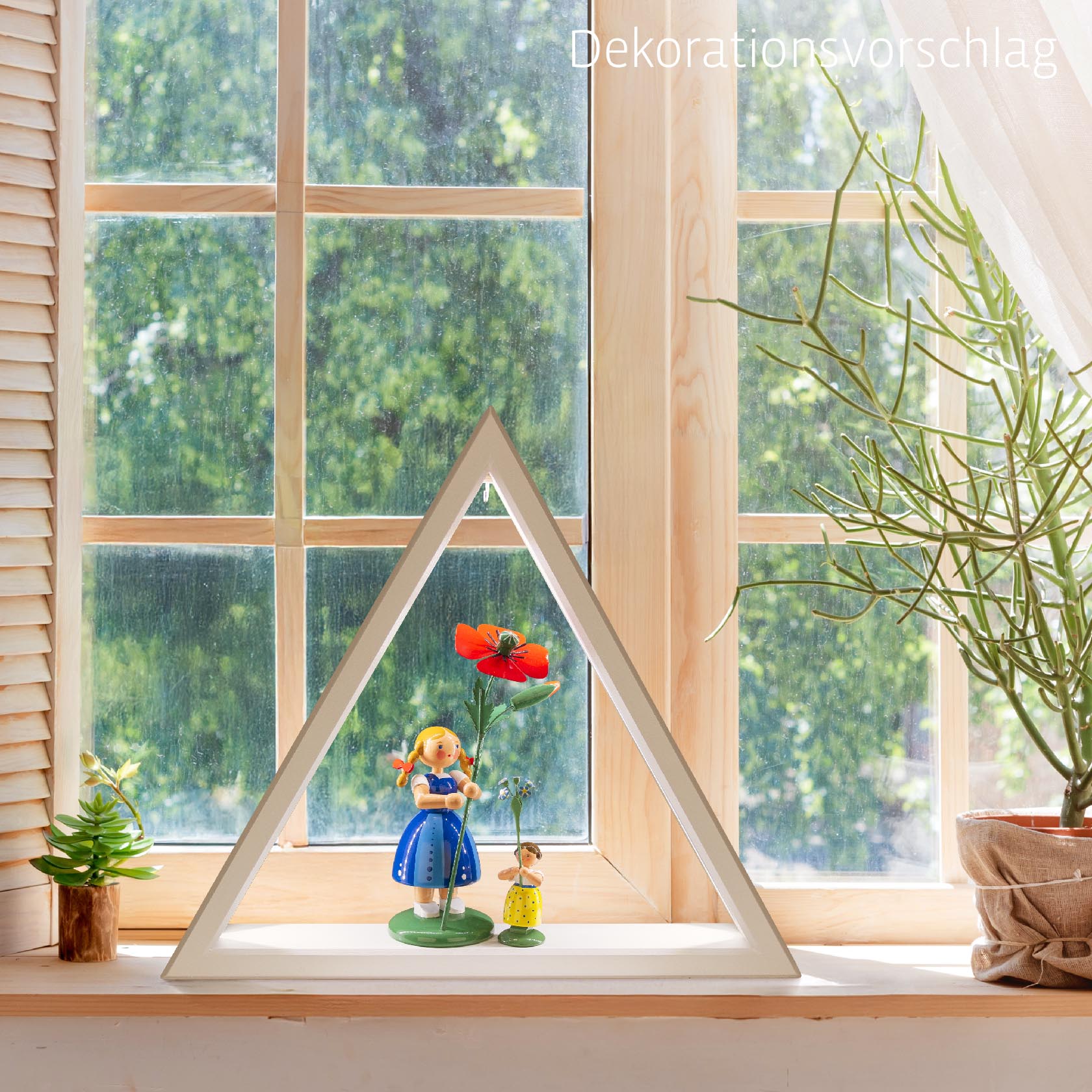 Weißes, beleuchtetes Dreieck mit LED-Band auf Fensterbank, mit Puppenhausfiguren und großer roter Blume im Inneren.