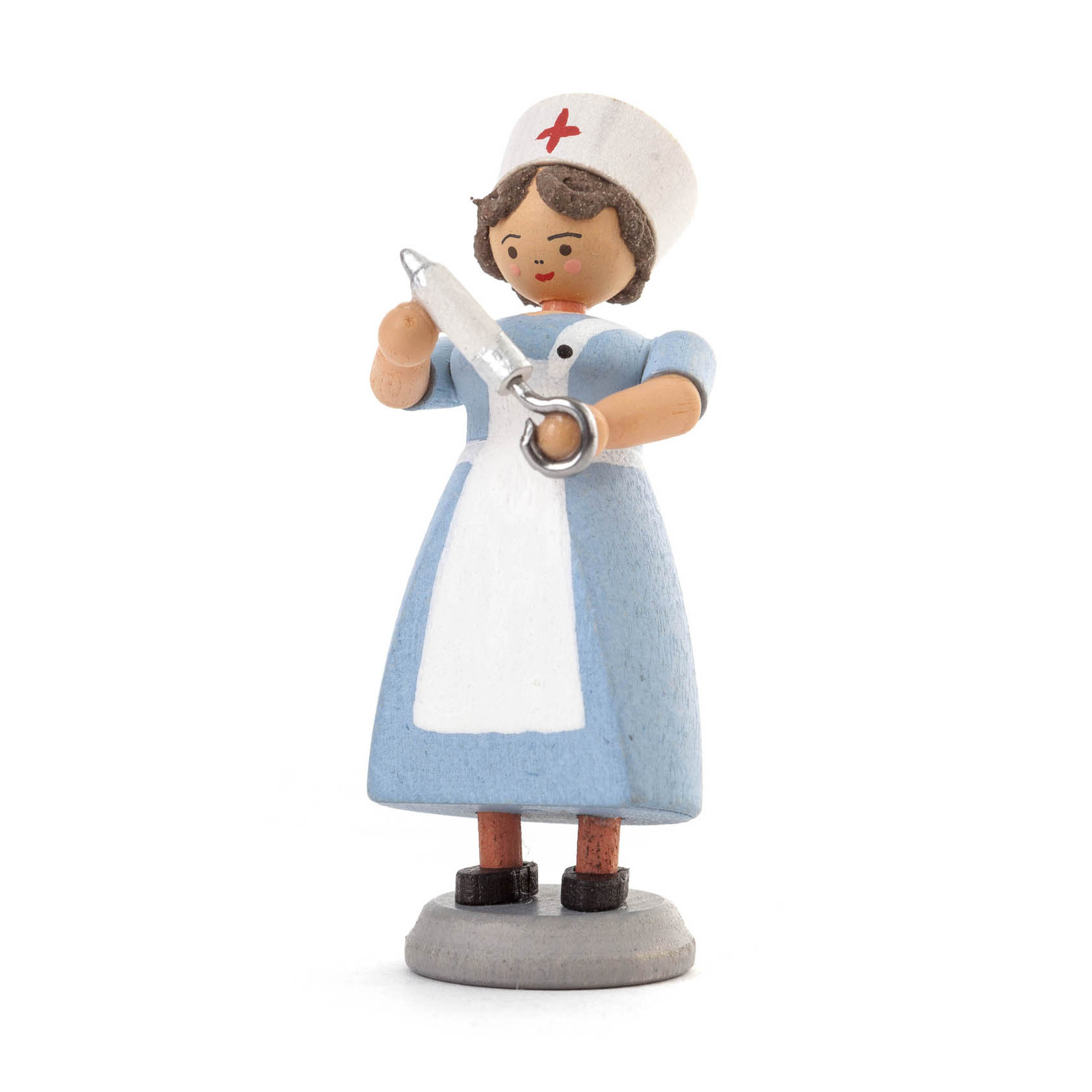 Holzfigur einer Krankenschwester in blauer Uniform mit weißer Schürze und Haube, hält eine Spritze in der Hand und steht auf einem grauen Sockel. im Dregeno Online Shop günstig kaufen