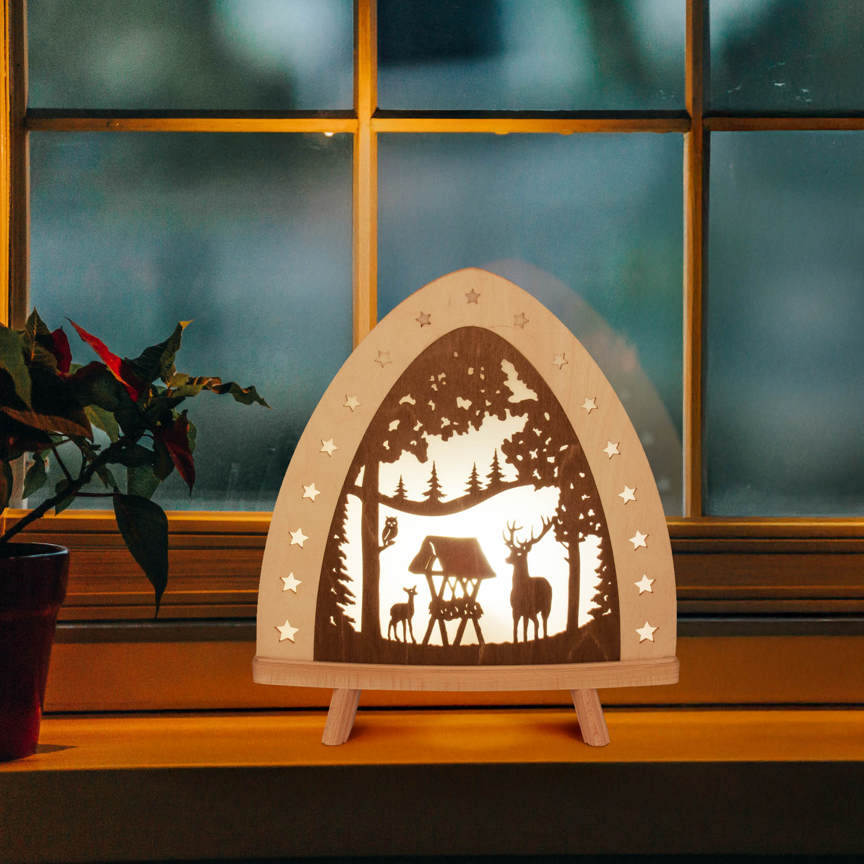 Decorative LED floor lamp with a deer silhouette scene, set against a window. The scene includes a forest background and small star-shaped cutouts.