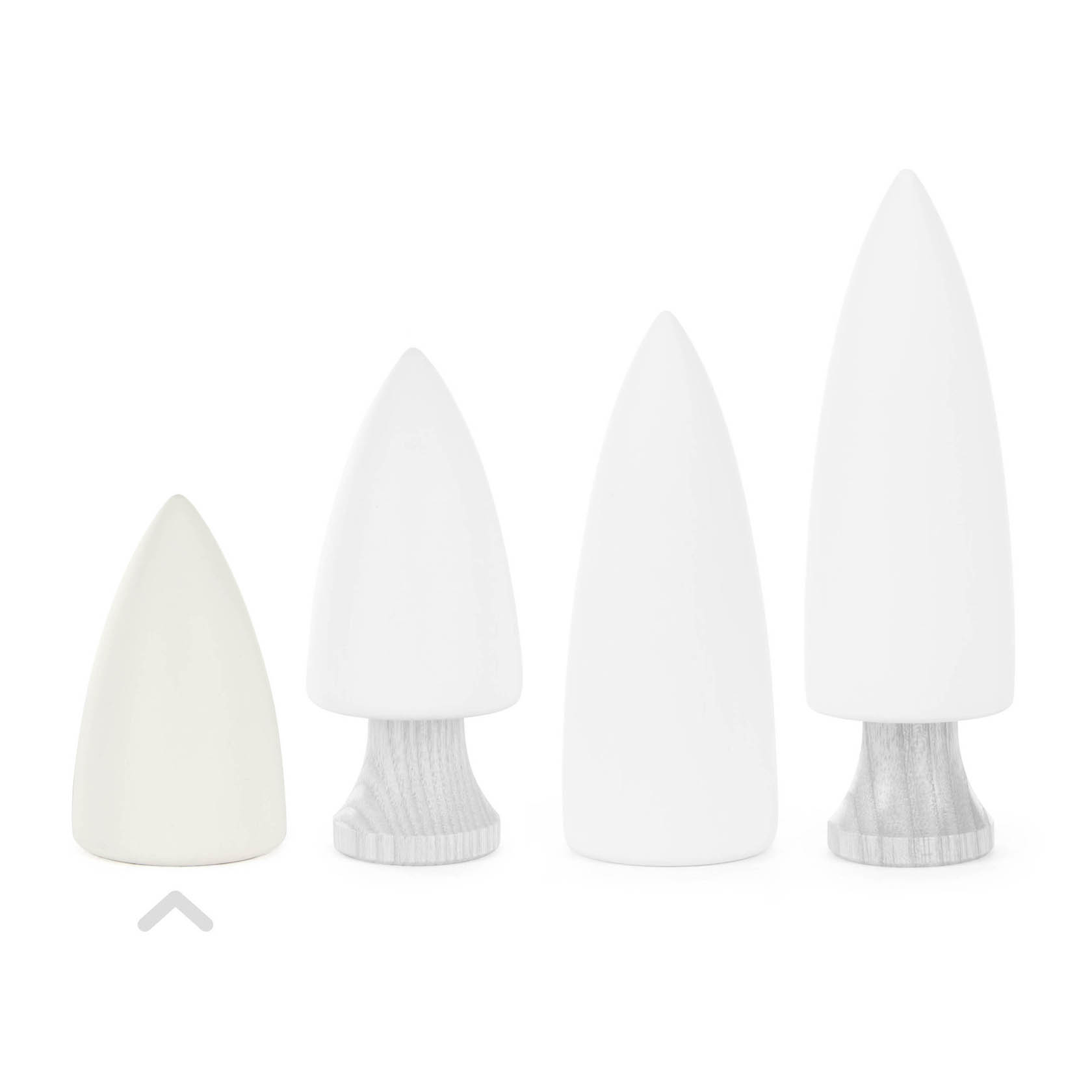 Four minimalist white tree figurines in varying sizes, two with wooden bases, and two without.