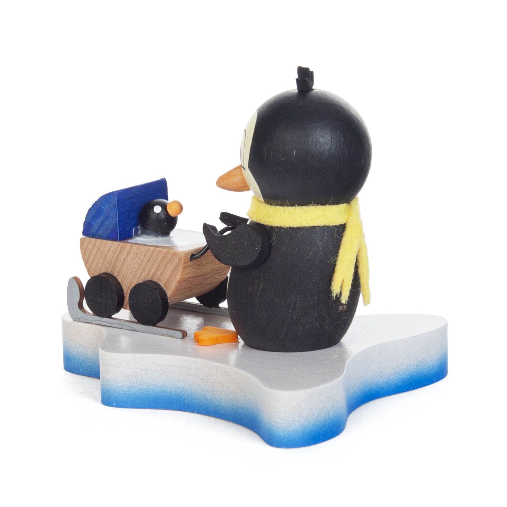 Holzpinguin mit gelbem Schal zieht einen hölzernen Kinderwagen mit einem kleinen Pinguin auf einem stilisierten Eisschollenboden.