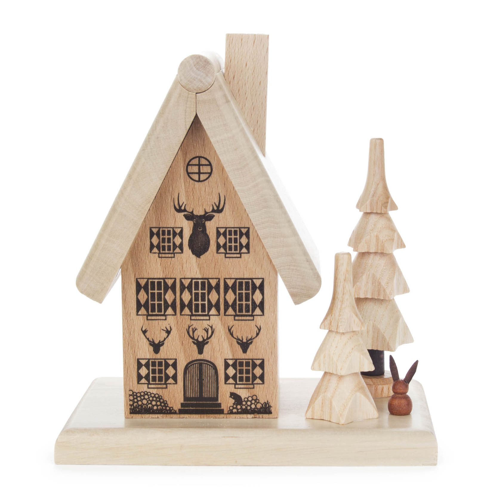 A decorative wooden house with triangular roof, smoked chimney, adjacent to two stylized wooden trees and a small figure, likely a rabbit. im Dregeno Online Shop günstig kaufen