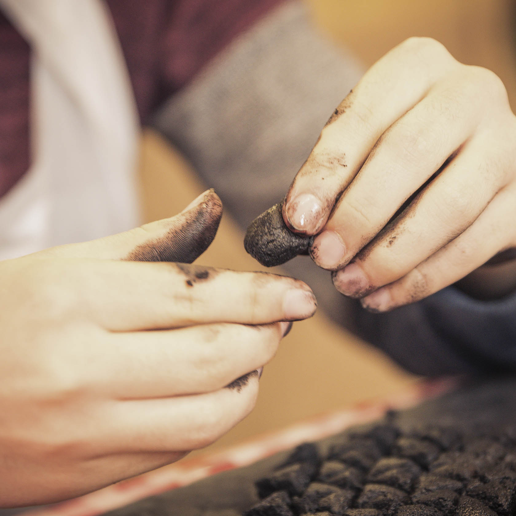 Close-up of hands shaping incense cones with darkened fingers.